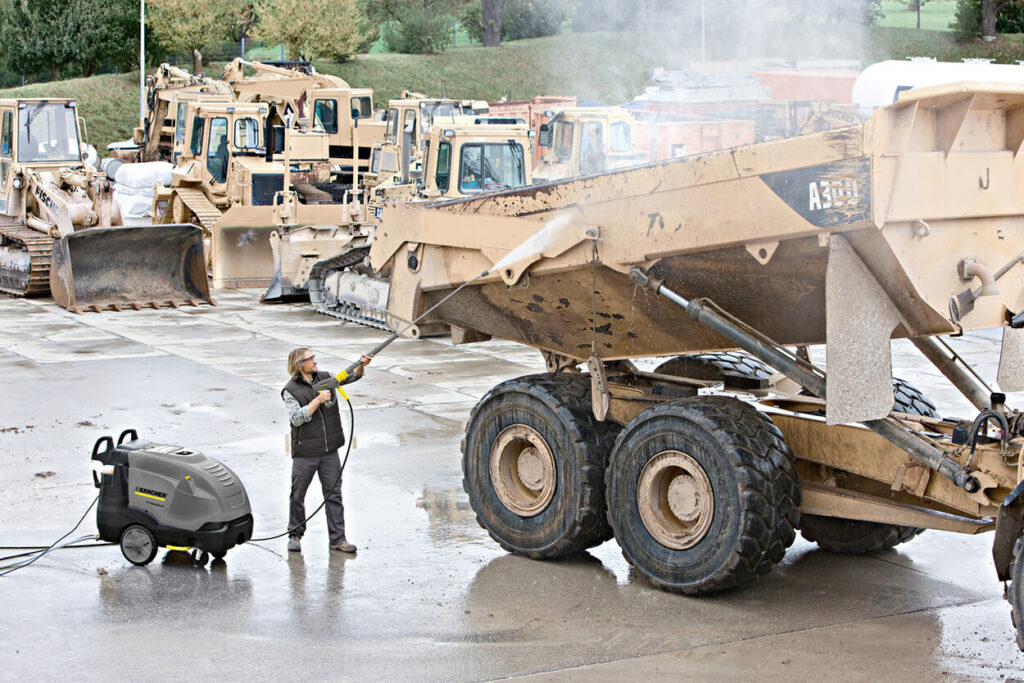 Man pressure washing truck in courtyard with HDS 7/10-4M Hot Water Pressure Washer