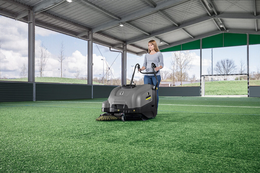 Woman using KM 75 40 W machine on football sports field