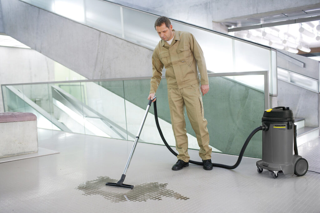 Man in overalls using NT 48/1 Hoover to clean wet floor