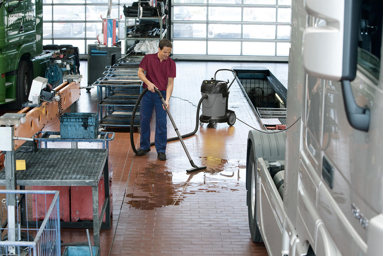 Man wearing red top using NT 70/1 Hoover to clean wet floor indoors