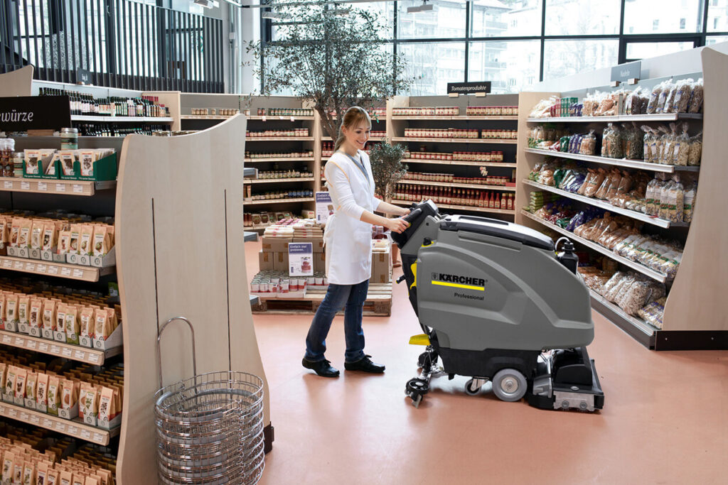 Smiling women cleaning supermarket floor with B 40 W scrubbing cleaning machine