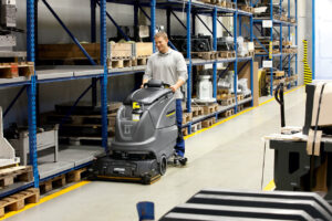Man operating B 80 W cleaning machine at empty warehouse