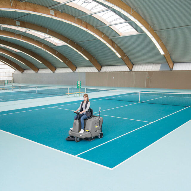 Women using KM 85/50 R ride-on vacuum sweeper on sports tennis court