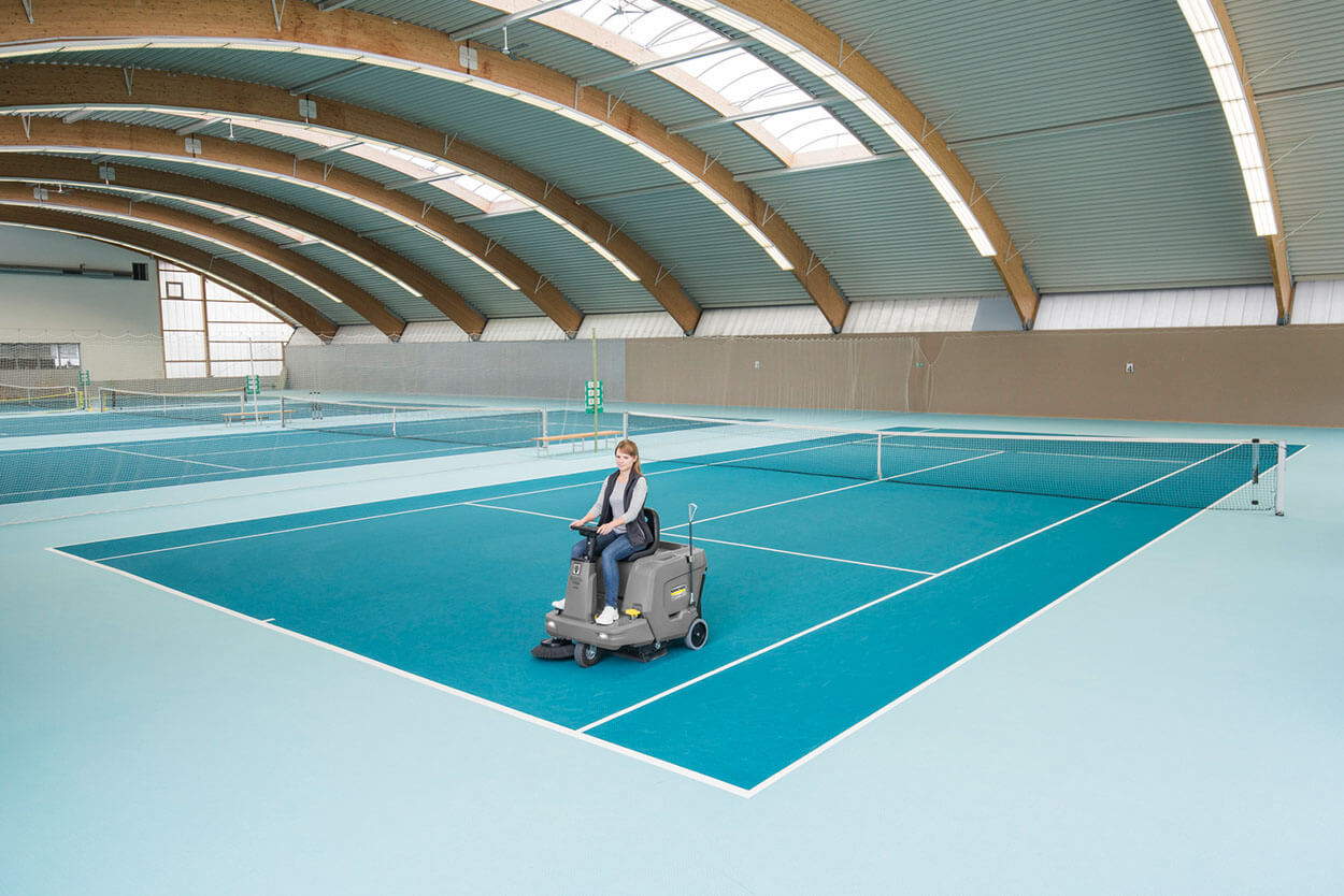 Women using KM 85/50 R ride-on vacuum sweeper on sports tennis court