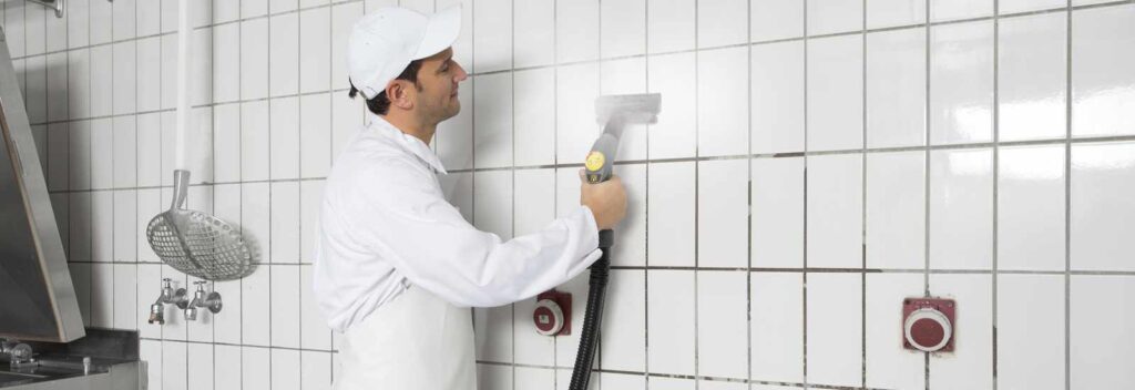 steam cleaning tiled walls in a commercial kitchen