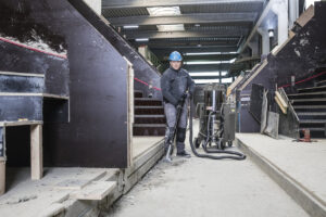 Man inside concrete factory wearing a blue helmet and sweeping the floor with IVS 100/75 Machine