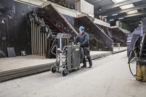 Man inside concrete factory wearing a blue helmet pushing IVS 100/75 Machine