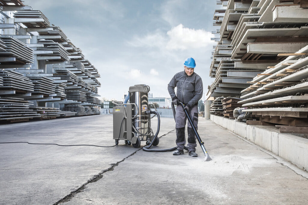 Man wearing blue helmet sweeping floor of courtyard with IVS 100/75 Machine