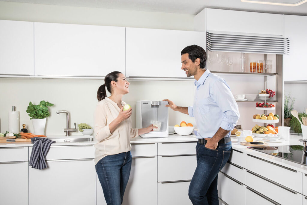 Man and woman dressed casually in bright white kitchen home, using WPD 50 Water Cooler