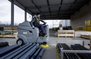 KM 100/120 battery ride on floor sweeper sweeping an industrial area